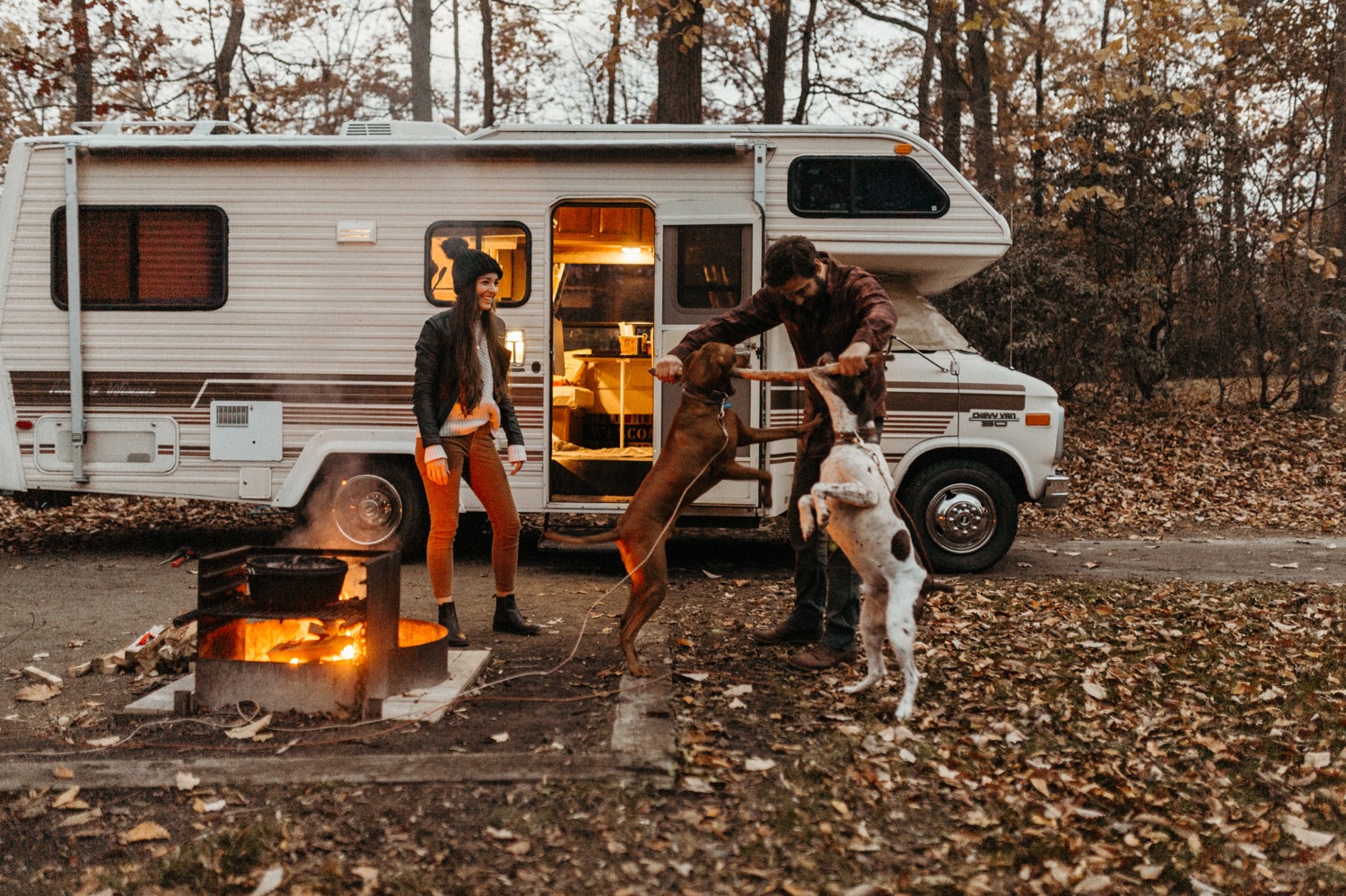 Chill Camping Engagement in Their Winnebago With a Bonfire and Their Dogs