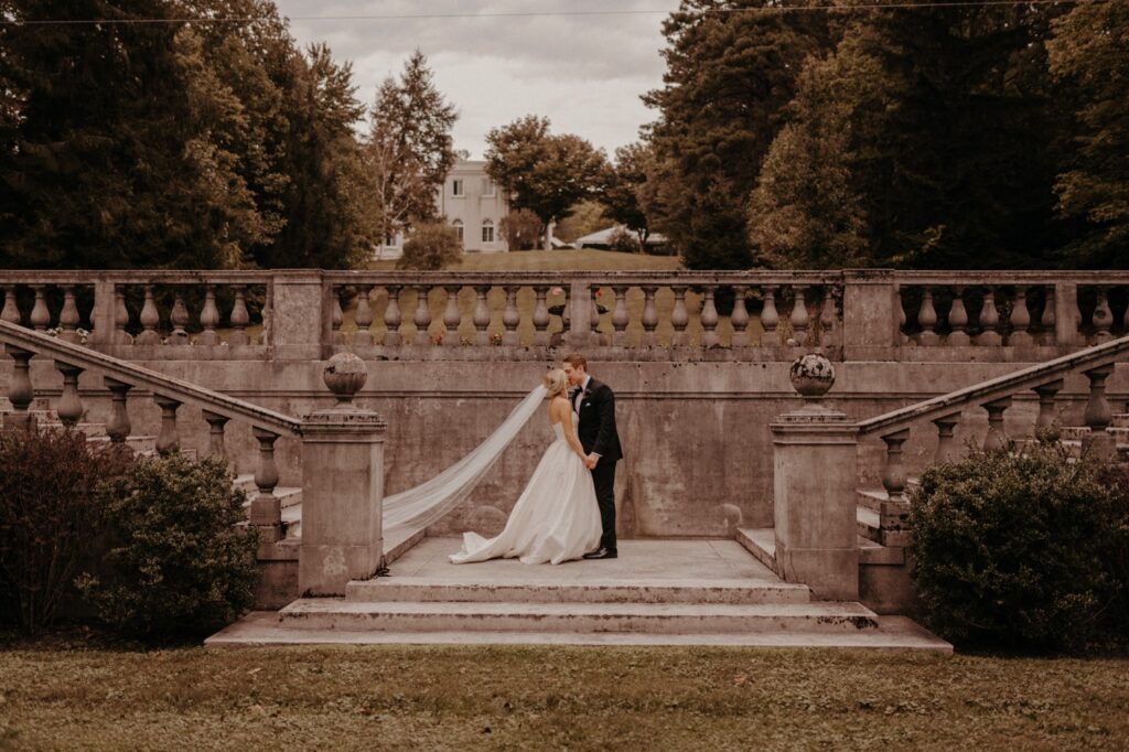 Bride and Groom kiss on stone steps at a wedding venue in maryland with beautiful gardens