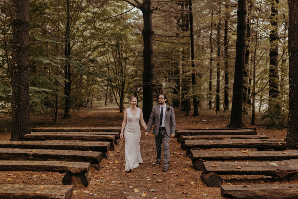 Outdoorsy wedding venue at pine cathedral ceremony with bride & groom holding hands