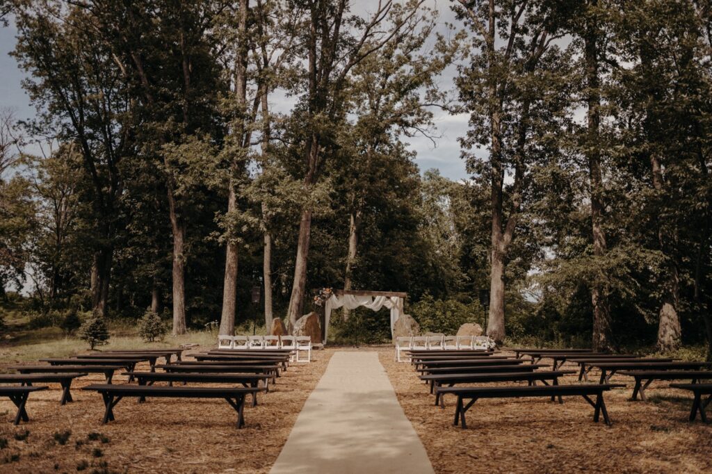 Farm wedding venue in Maryland with an outdoor ceremony in the woods, pine benches, cathedral style